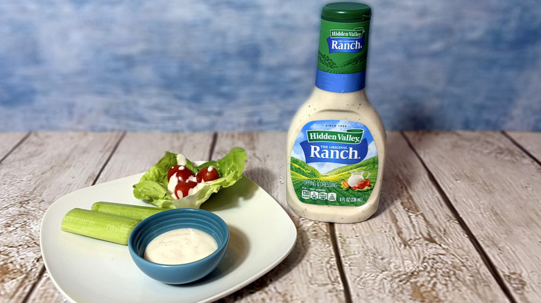 A bottle of original ranch next to a plate with salad and a bowl of dressing