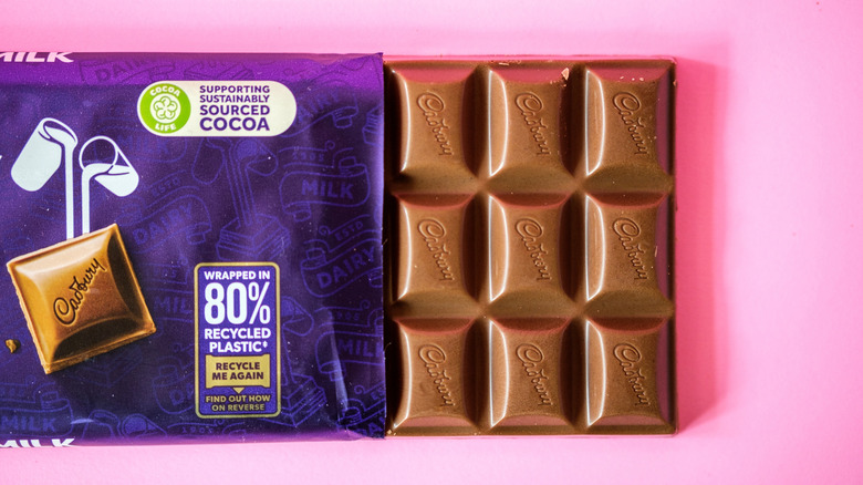 A bar of Cadbury Dairy Milk has some of the chocolate poking out of the wrapper.