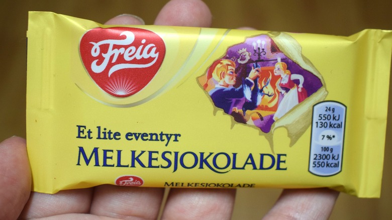 A hand is holding a bar of Freia Melkesjokolade.