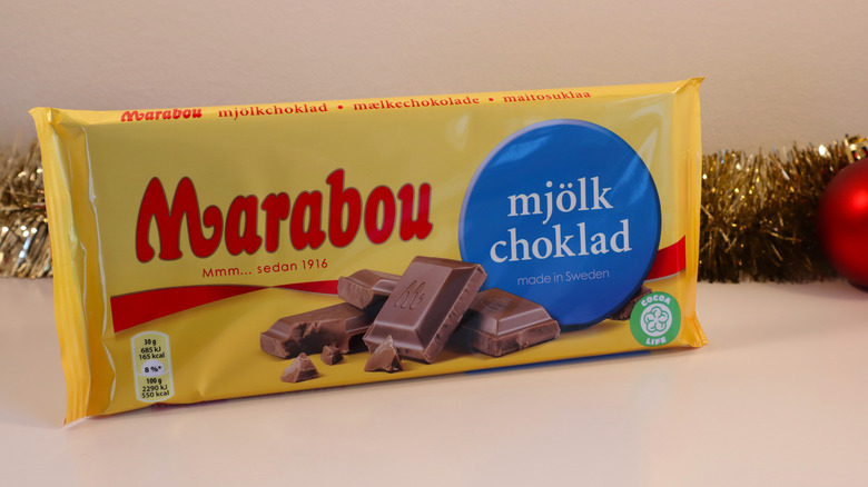 A bar of Marabou Mjölkchoklad is surrounded by Christmas decorations.