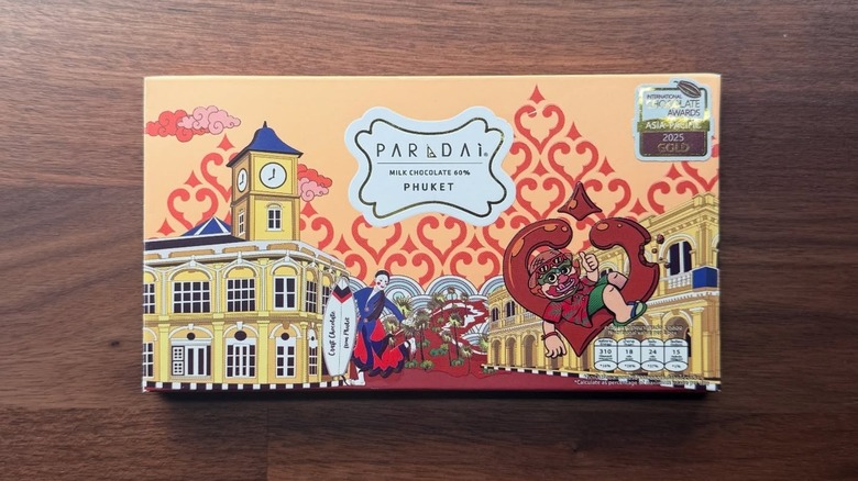 A bar of Paradai Phuket Milk chocolate is set on a wooden table.