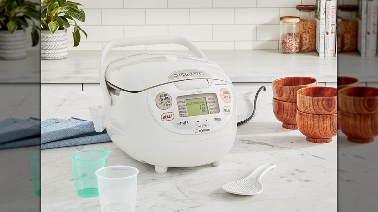 Zojirushi Neuro Fuzzy rice cooker and warmer on a kitchen counter with spoon and cups