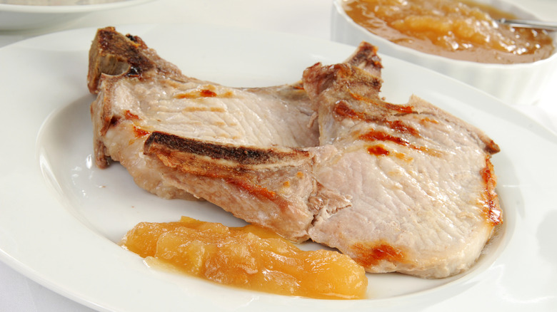 Pork chops and a dollop of applesauce on a white plate