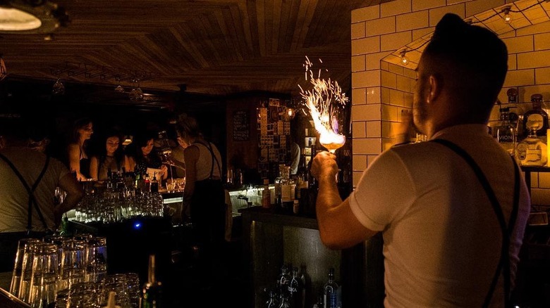 bartender holding flaming cocktail