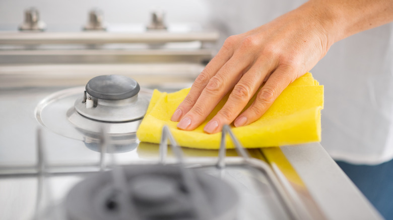 person cleaning stove with towel