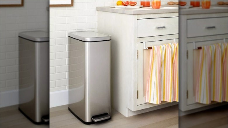 Slim step trash can next to counter in white kitchen