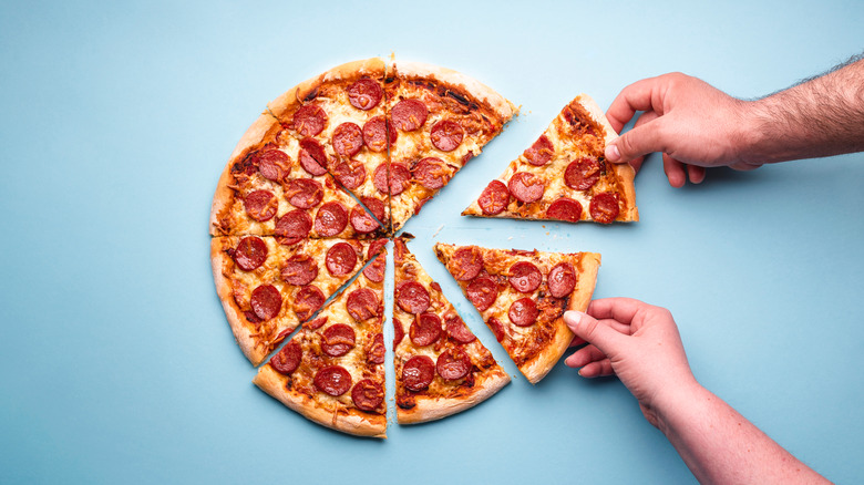 hands grabbing pizza slices