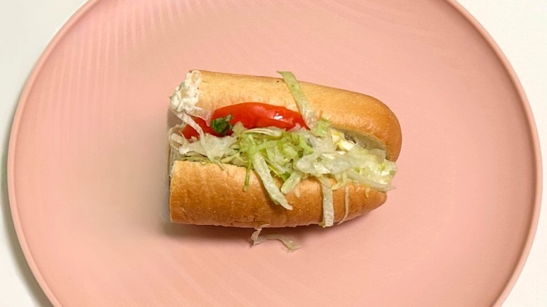 A Wawa tuna salad hoagie on a pink plate against a white background