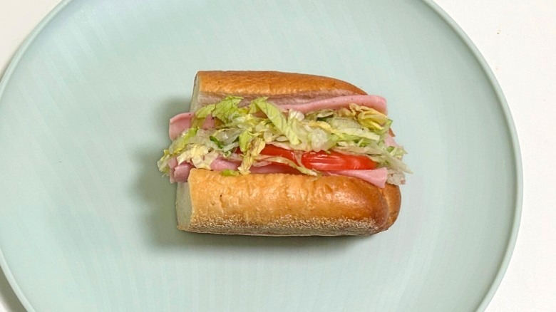 A Wawa ham hoagie on a green plate against a white background