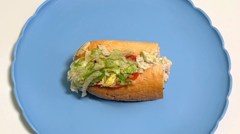 A Wawa chicken salad hoagie on a blue plate against a white background