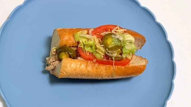 A Wawa buffalo chicken cheesesteak hoagie on a blue plate against a white background