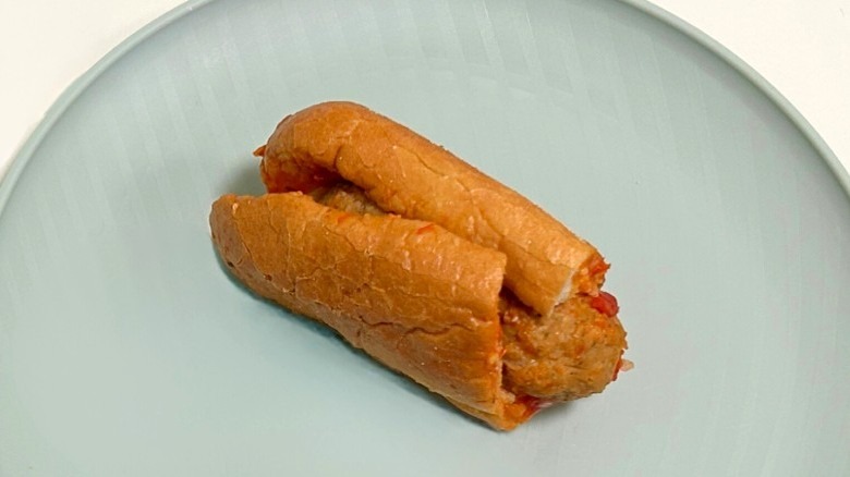 A Wawa meatball parmesan hoagie on a green plate against a white background