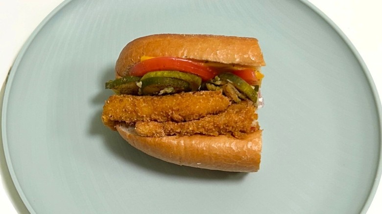 A Wawa dill pickle ranch chicken sandwich on a green plate against a white background