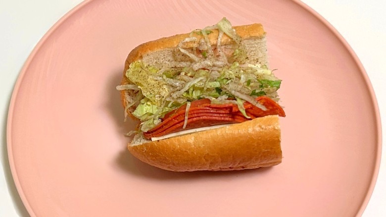 A Wawa pepperoni  hoagie on a pink plate against a white background