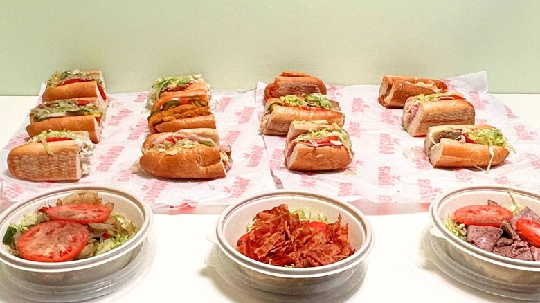 Several Wawa hoagies and no-bun hoagies on a counter against a green wall