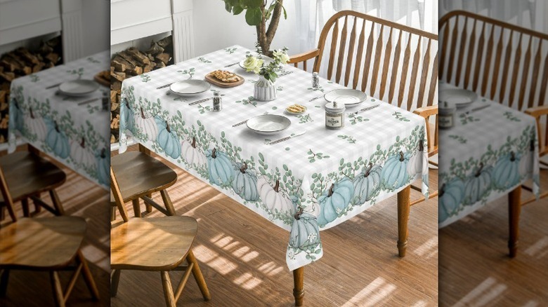 Blue pumpkin tablecloth on table with plates and flowers