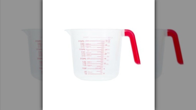 Measuring cup with red handle and writing on white background