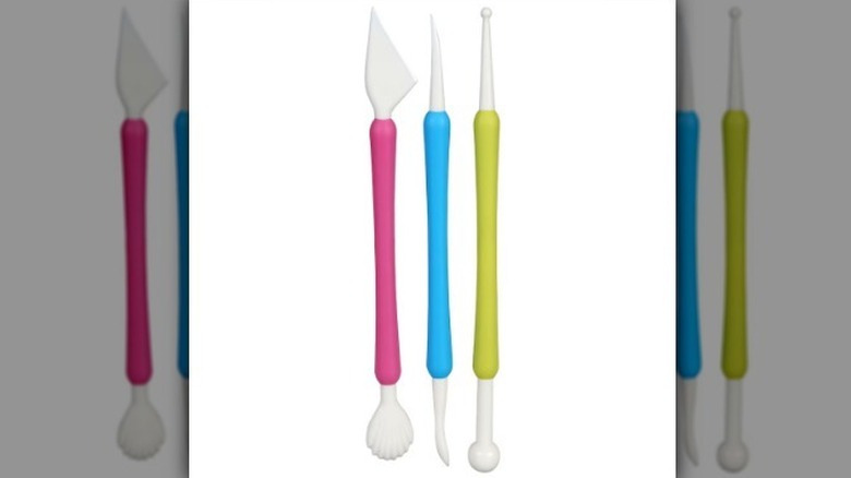 Pink, blue, and green cake decorating tools on white background