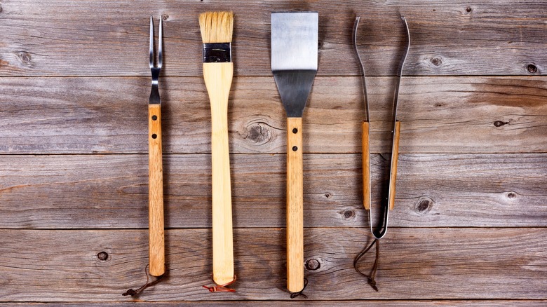 Selection of barbecue grilling tools on a rustic wood table