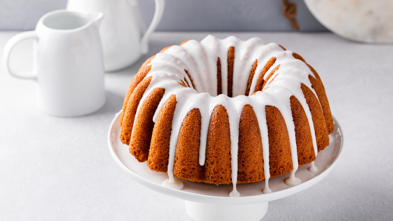 A Bundt cake on a raised platform with white glaze