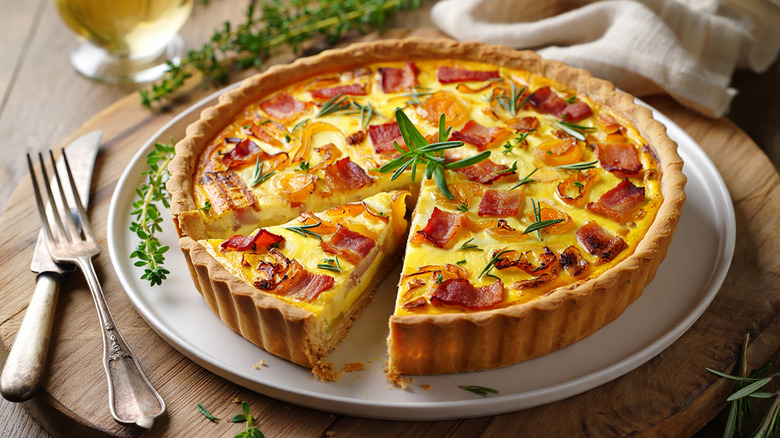 A perfectly baked quiche Lorraine garnished with rosemary sprigs