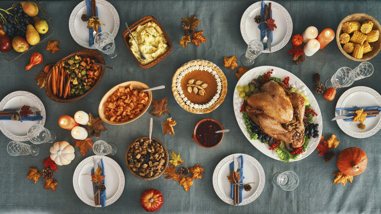 Top-down view of a table set with dinnerware and food for Thanksgiving
