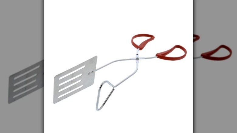 Metal tong turner with red handles on white background