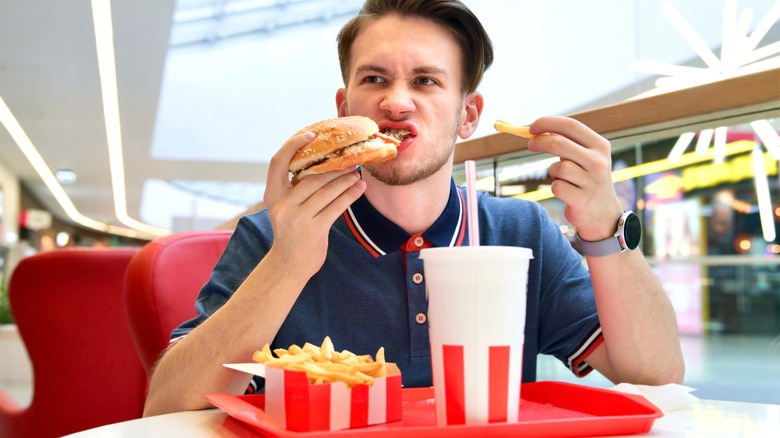 guy eating burger and fries