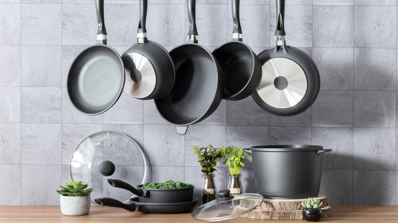 Modern kitchen with some pots and pans on a countertop, and others hanging