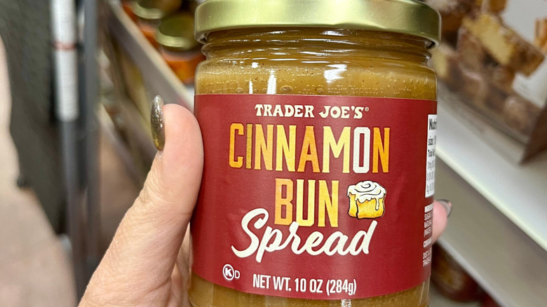 A hand holding Trader Joe's Cinnamon Bun Spread