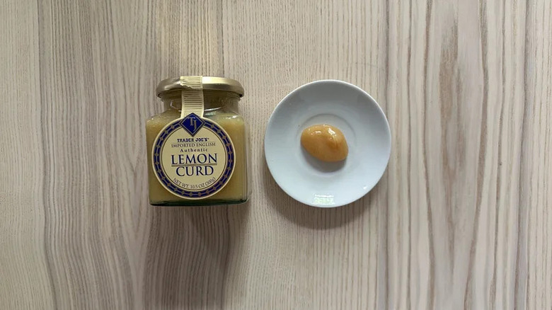 Jar of Trader Joe's Lemon Curd next to a sample on a plate with wood background