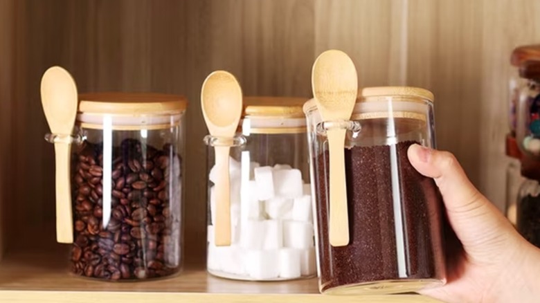 glass storage containers pack with bamboo lids and spoons holding coffee beans, ground coffee, and sugar cubes