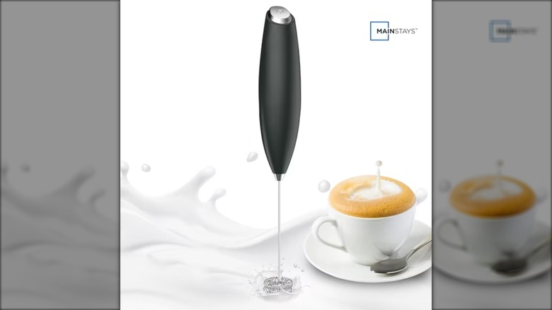 Stainless steel Milk frother next to a cup of coffee