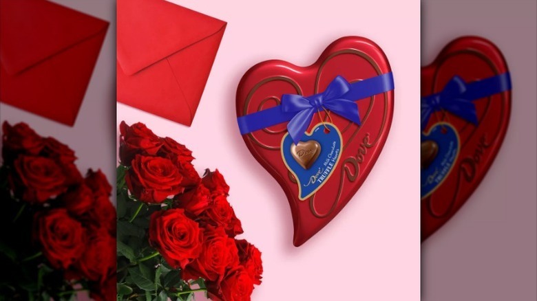 Dove heart box on pink background with flowers and card