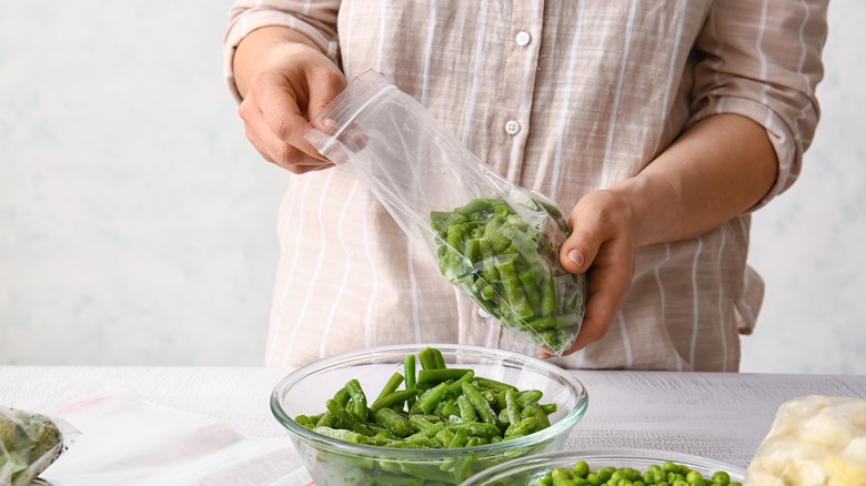 person putting green beans into bag