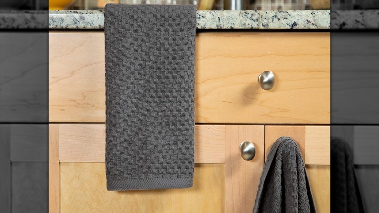 The gray Cotton Craft terry towels hanging down from a kitchen counter and from a cabinet door knob