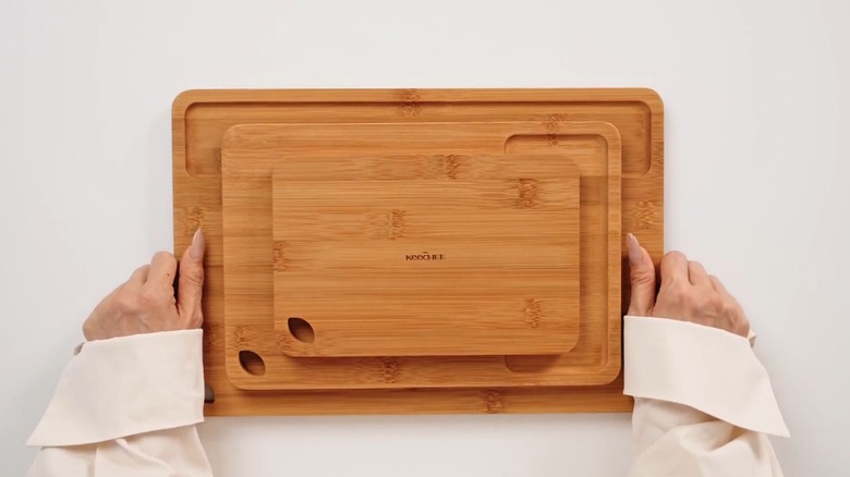 Top-down view of setting the three-piece keechee bamboo cutting board set onto a white counter