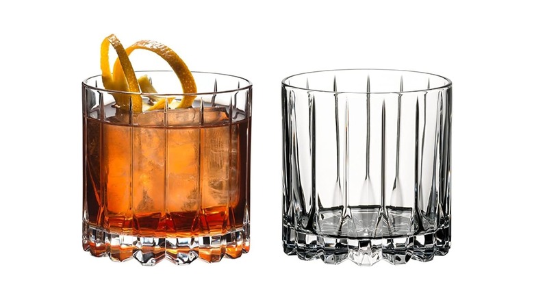 A Riedel rocks glass (left) with a spirit, ice, and orange peel spiral next to an empty rocks glass (right)