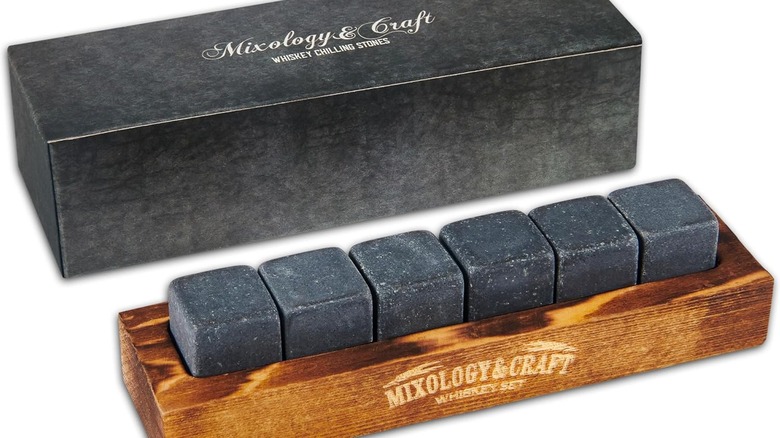 Set of Mixology & Craft dark granite whiskey chilling stones in a wooden storage block with the box sitting behind it