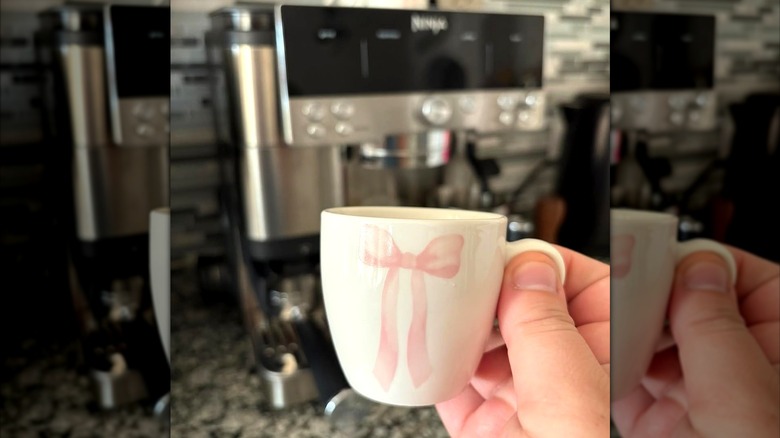 white espresso mug with pink bow and espresso machine in the background