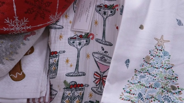 Assorted Christmas-themed kitchen towels, with the center one featuring Christmas cocktail designs