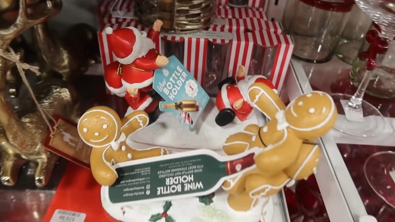 A wine bottle holder with two gingerbread man statues that hold the bottle up