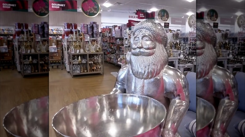 A silvery life-sized statue of Santa, holding an equally silvery punch bowl