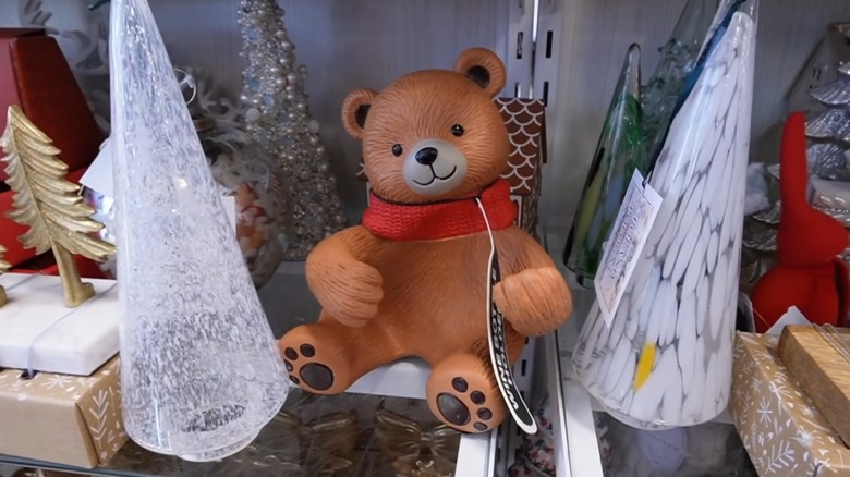 A teddy bear statue with open arms meant to hold an entire bottle of wine