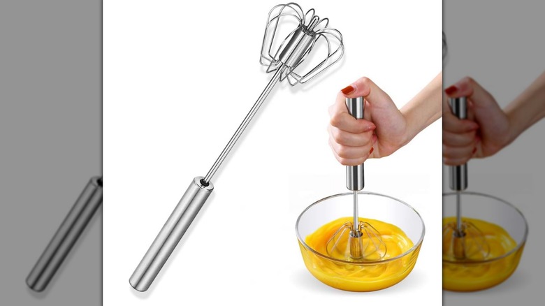 Stainless Steel Eggbeater and a hand beating an egg in a glass bowl on a white background