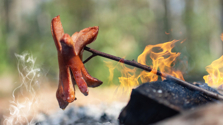Cervelat sausage being grilled over fire