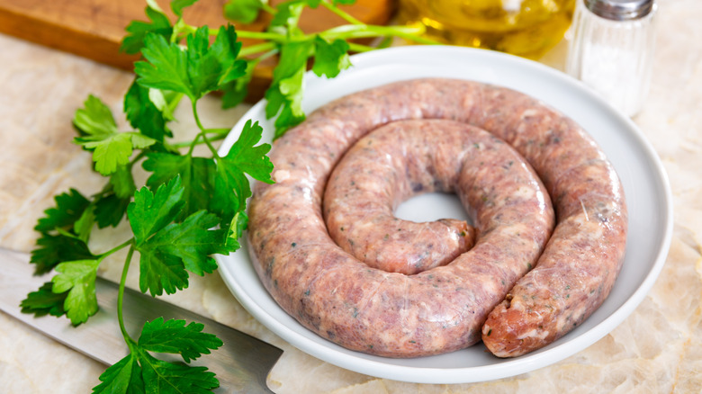 Fresh Cumberland sausage on a white plate with cilantro on the side