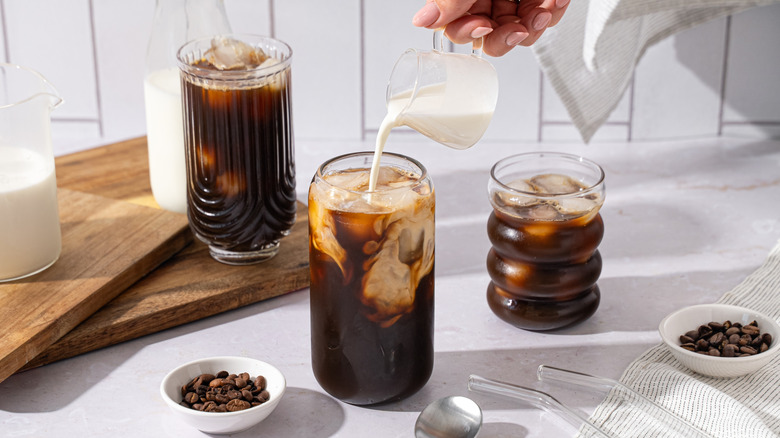 Hand pouring creamer into coffee