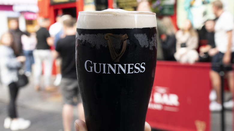 person holding glass of Guinness outside