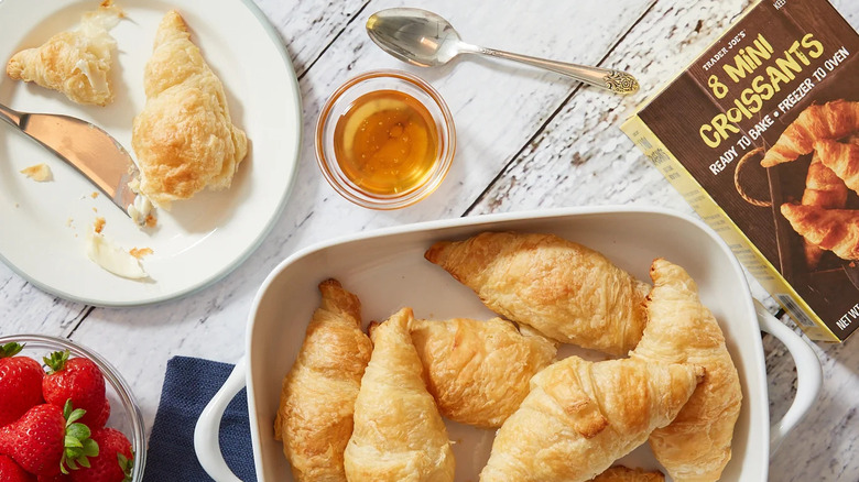 Mini croissants on white platter with honey and strawberries